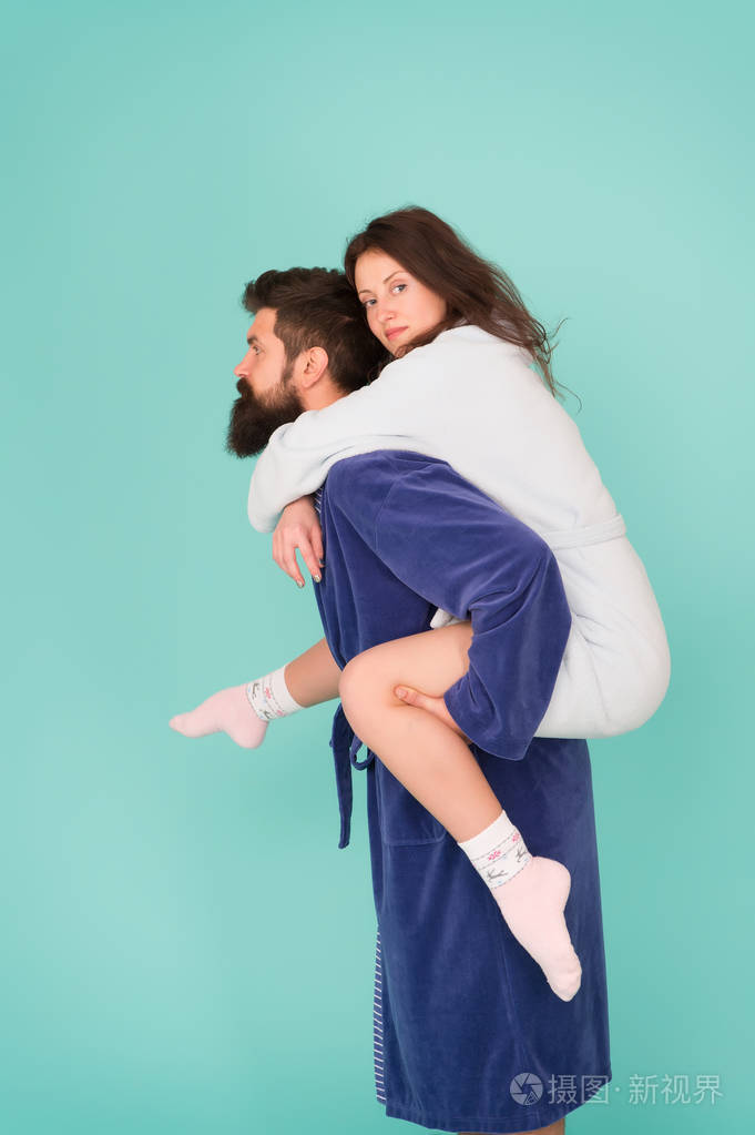 可靠的支持英俊的年轻人背着漂亮的女人一对穿着浴袍的情侣玩得很开心