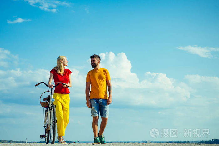 文本的天空背景。美丽的夏日。暑假。享受在一起的时光。夏日情侣。一对穿着夏装的夫妇骑自行车。说话。蓝天背景复制空间。