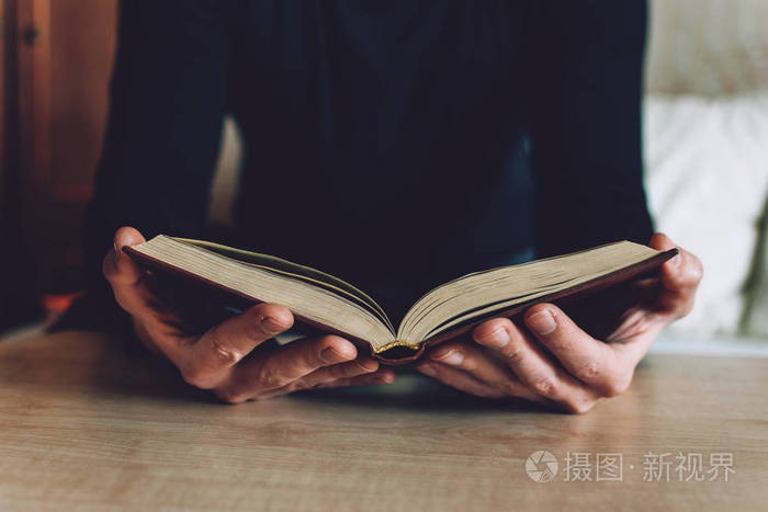 手里拿着打开的书的人男人手里拿着一本精装书