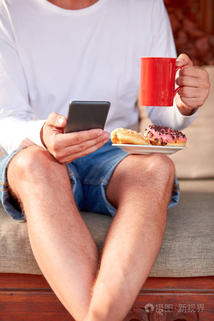 男人坐在露台沙发上喝咖啡茶吃东西