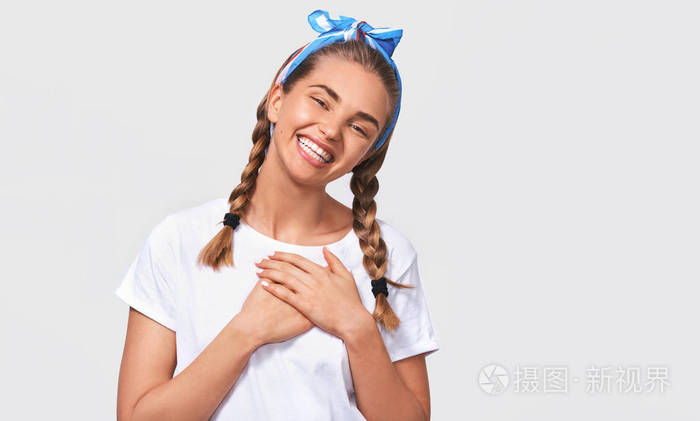 一个善良美丽的年轻女子微笑着双手放在胸前看着镜头穿着白色t恤衫在