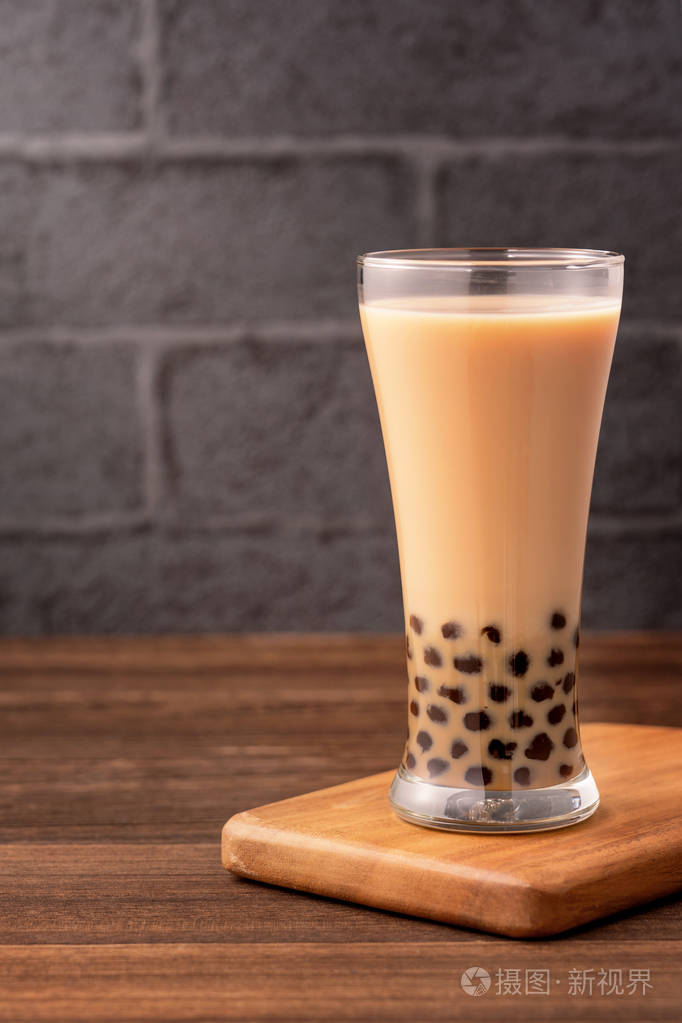 美味的泡泡奶茶,木桌上有木薯珍珠球,背景为深灰色砖块,台湾流行的