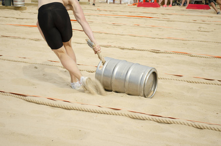 一个穿短裤的人在沙滩上拉一根绳子.照片