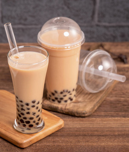 外卖奶茶美味的泡泡奶茶用吸管在木桌背景上,减塑概念去台湾,特写