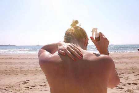 在海滩上背上涂防晒霜的女人图片