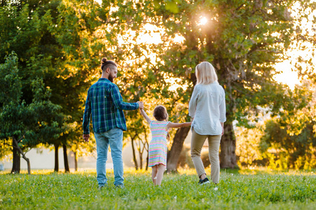 快乐的年轻家庭在绿色的大自然里一起度过时光.照片