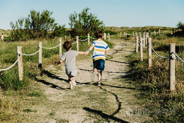 两个兄弟姐妹手牵手在田野里奔跑快乐而自由