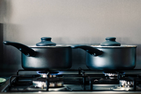 煤气灶上的两个黑色发亮的锅在里面做饭时冒着热气照片