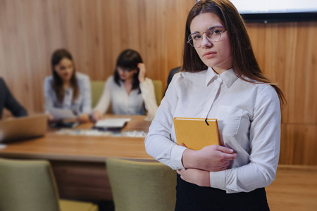 青年上班族年轻迷人时尚的上班族女孩戴着眼镜,手里拿着笔记本,背景是