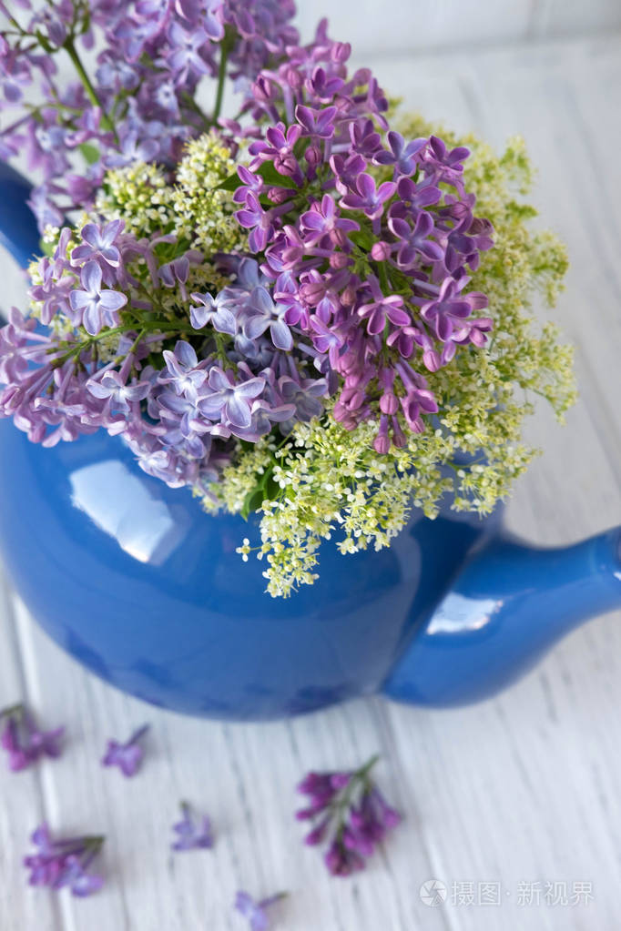 蓝色茶壶里的丁香木质背景上有一个题字的地方丁香花