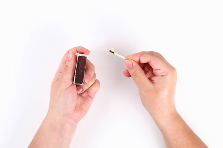 火花点火激发均质压燃女孩从一盒白底火柴中点燃一根火柴.俯视图.照片