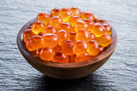 碗里的红色鱼子酱在灰色石墨背景上.照片