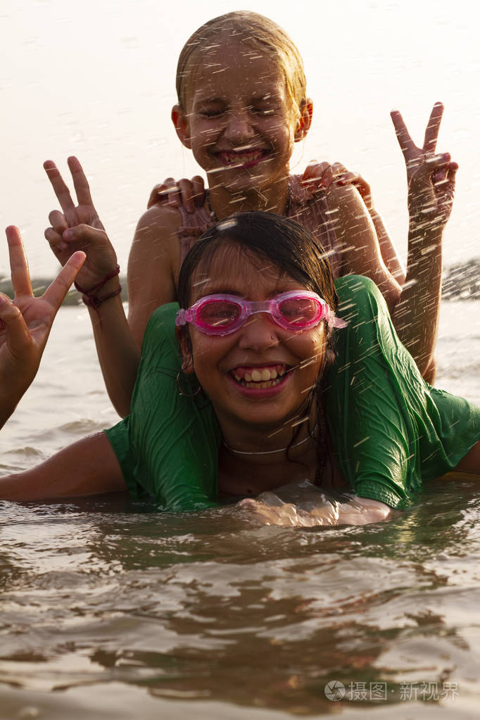 快乐的孩子们穿着湿衣服在河里玩耍年轻的朋友在河里游泳夕阳下两个