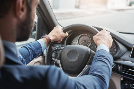 特写照片,年轻的胡子商人穿着正装坐在他的新舒适的汽车方向盘照片