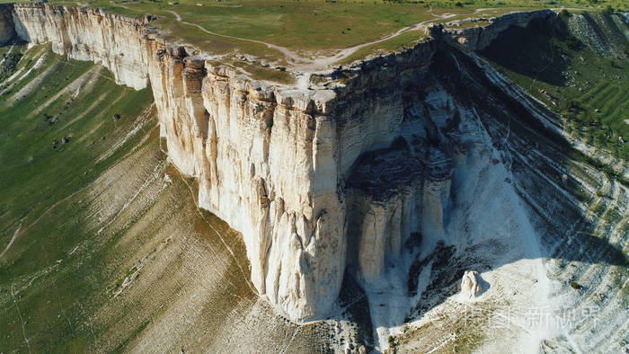 鸟瞰白色悬崖顶覆盖着绿色的草白色的小径和小山以上的草地在阳光明媚