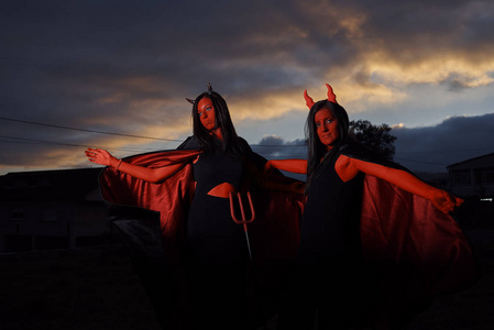 两个穿着魔鬼服装的年轻女人在万圣节照片