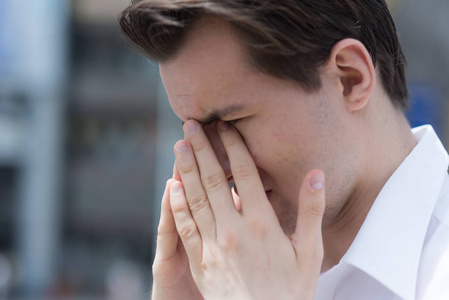 一个年轻人因花粉过敏而眼睛发痒,流泪,肿胀照片