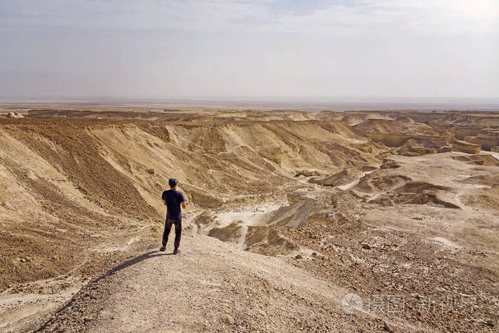 在沙漠中发现死气沉沉领土的年轻旅行者.流浪癖.男性旅游致富目的地.