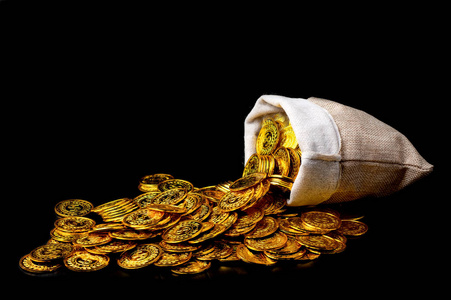 在黑色背景上把金币堆在宝袋里照片