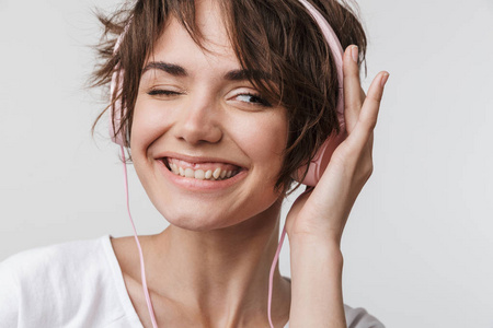 音乐墙非常兴奋快乐的女人在白色的墙壁背景上独自摆姿势,戴着耳机听