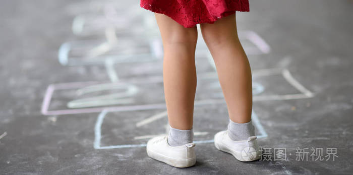 小女孩的腿特写和沥青上画的跳房子阳光明媚的一天孩子们在户外的操场