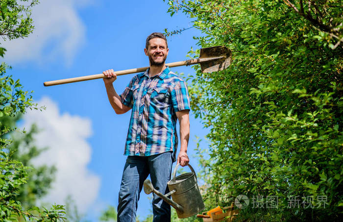 一个留着胡子的时髦男人拿着铲子和水壶.春季园