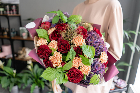 鲜切花玫瑰一大束漂亮的混合花在女人手里.花店概念.美丽的鲜切花束.
