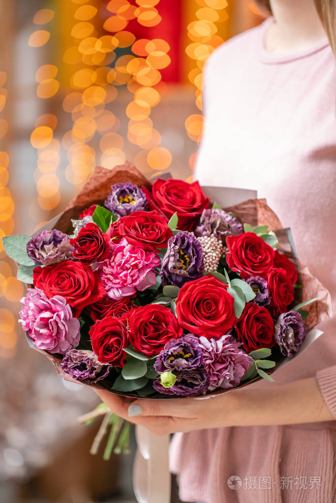 一束美丽的混合花在女人手中花店概念美丽的鲜切花束送花背景上有花环