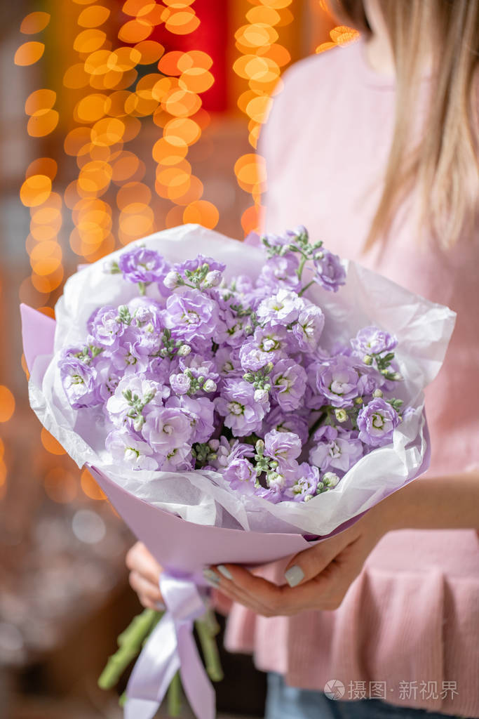 一束美丽的丁香花在女人手中花店概念美丽的鲜切花束送花背景上有花环