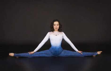 女杂技演员,体操运动员,身穿蓝白相间套装的年轻运动员,练习杂技.照片