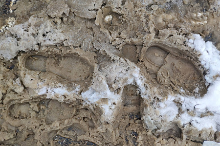 泥泞的雪地上鞋子的脚印.照片