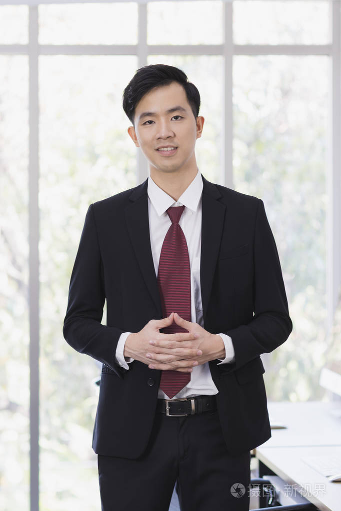 亚洲商人站在办公室里摆姿势