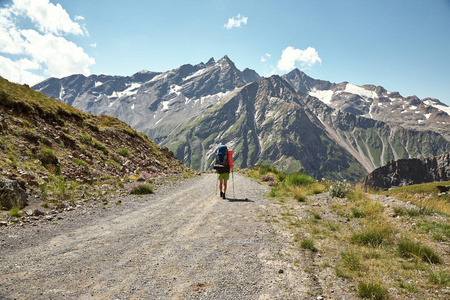 登山者在山间小路上.背着背包徒步旅行的人照片