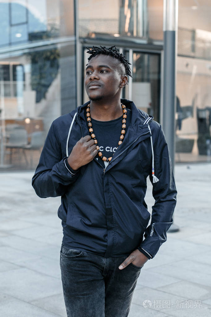 非裔美国人在街上迷人的侧面肖像穿着牛仔夹克的时尚非洲男人在城市里