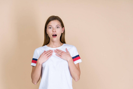 简直风格一个年轻的女人手放在胸前,站在柔和的米色背景上照片