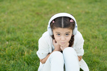小女孩坐在耳机里听音乐,欣赏夏日大自然.新技术.技术概念照片