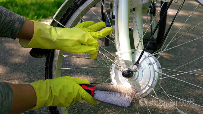 Cyclist in yellow gloves is cleaning the electric bicycle motor 