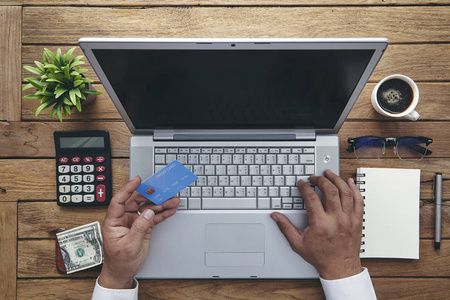 持笔记本龙持信用卡和使用笔记本电脑的人.网上购物照片