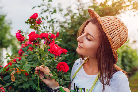 闻味道在花园里采花的年轻女子.闻着玫瑰的味道,剪下玫瑰.