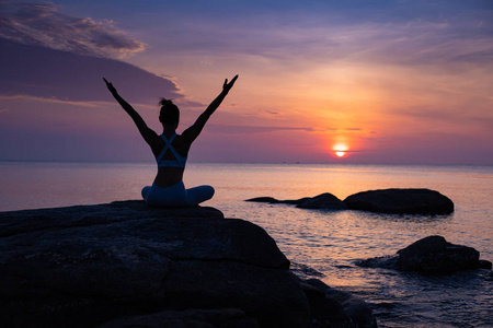 亚洲女孩在海滩上练习瑜伽日出的一天照片