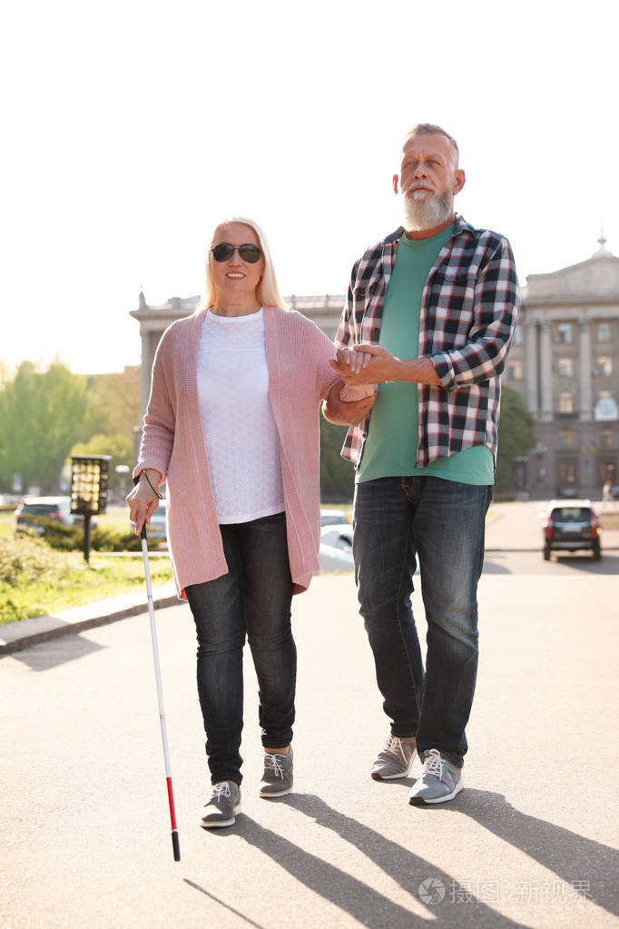 成年男子扶长拐杖盲人户外行走
