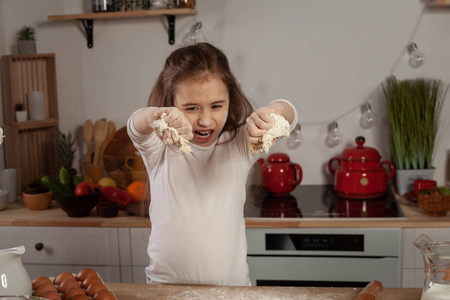 烘烤的衬衫一个漂亮的小女孩穿着白衬衫在厨房里做面团用来烤面包.