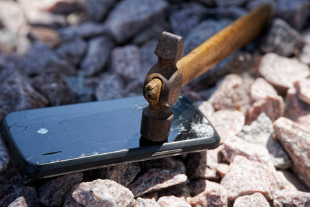 砸电脑智能手机碎玻璃用锤子砸在碎石上.选择性聚焦照片