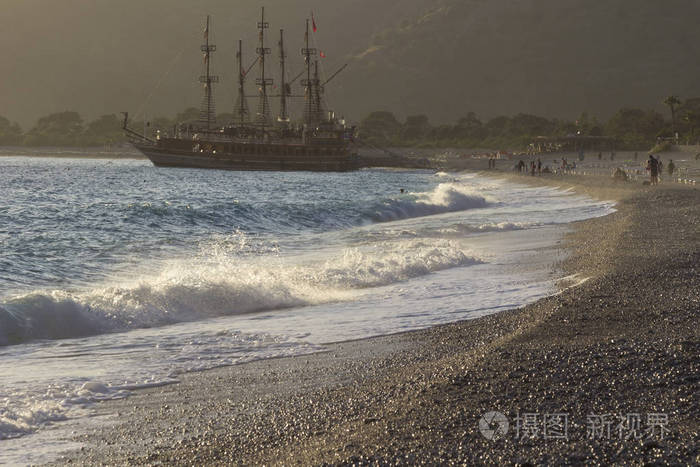 地中海海滩上金色的夕阳。一艘游艇停泊在岸边