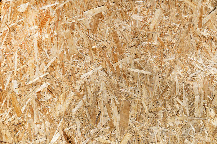 刨花板特写背景空白压制木屑的纹理木板上的锯屑在压榨机下相似的