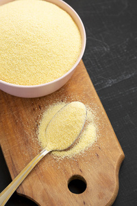 dry semolina durum flour in a pink bowl over black surface, low