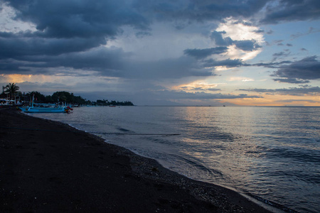 蓝色的一小时在平静的海洋和黑色沙滩上和巴厘岛的蟒蛇照片