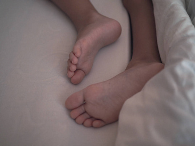 婴儿的脚睡在婴儿床上一个蹒跚学步的小男孩,尿在裤子里,在t一个蹒跚