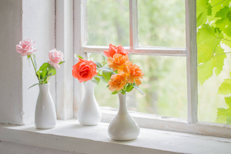 旧木窗台上花瓶里的美丽玫瑰照片