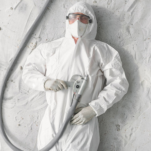 一个身穿白色防护服,口罩和塑料透明眼镜的男子.照片